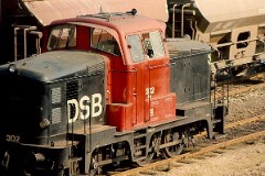 MH 302 photographed at the shunting yard in Fredericia, 3. March 1976.  Built by Frichs, Denmark in a number of 120. The class was put in service in 1960 - 1965. C0. Dieselhydraulic 8-cyl MAN engine. 440 hp. Max speed 60 km/h - 37 mph. Length 9 440 mm. Weight 45 metric tonnes. MH 302 was put in service in 1960. Withdrawn from service in 1998. The same year sold to Struer Jernbaneklub (Museumrailway) where it still remains in service.